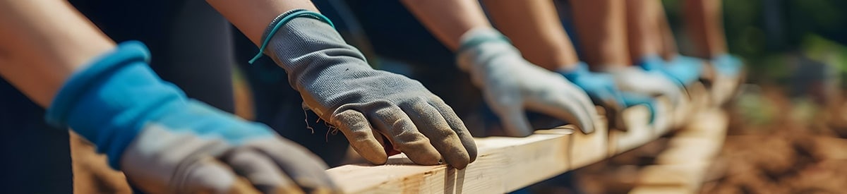 people working on a project outdoors wearing gloves and working with wood